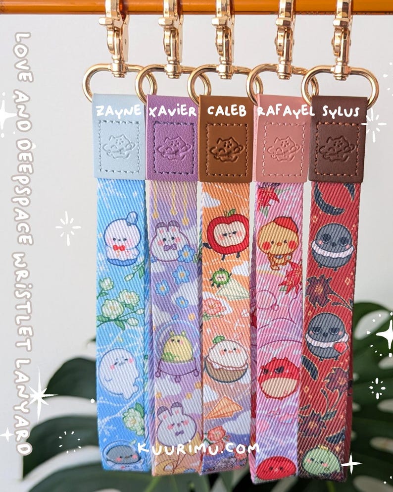 May include: Five fabric wristlet lanyards with gold-tone metal clasps and leather-like tabs embossed with a planet icon. Each strap features unique cartoon character prints and the names Zayne, Xavier, Caleb, Rafayel, and Sylus. Text reads LOVE AND DEEPSPACE WRISTLET LANYARD and KUURIMU.COM.