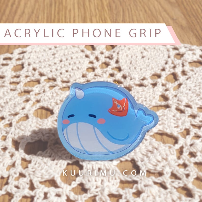 May include: A blue and white acrylic phone grip shaped like a cartoon narwhal with a red fin. The text "KUURIMU.COM" is printed below the narwhal.