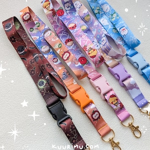 May include: Five fabric lanyards featuring colorful cartoon character prints and plastic side-release buckles. The lanyards come in brown, orange, pink, purple, and blue, each with a gold-toned metal swivel lobster clasp and the text kuurimu.com.