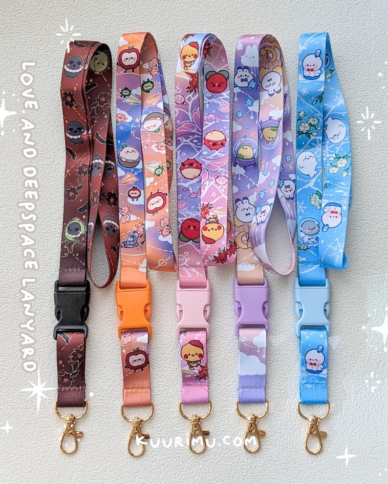 May include: Five fabric lanyards with plastic side-release buckles and gold-tone metal swivel hooks. Each features unique cartoon character prints in brown, orange, pink, purple, and blue. Text on the left reads LOVE, AND DEEPSPACE LANYARD.