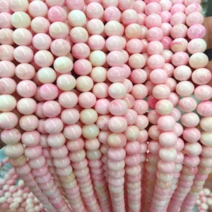 Peut inclure: Plusieurs brins de perles rondes roses et blanches. Les perles ont une finition brillante et présentent des nuances de rose, créant un aspect marbré. Idéal pour la création de bijoux et l'artisanat.