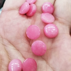 Peut inclure: Une collection de dix pierres précieuses rondes en cabochon roses. Les pierres précieuses sont lisses et polies.