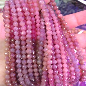 Op de afbeelding: Een streng roze facetgeslepen edelsteen kralen. De kralen zijn klein en rond en hebben een glanzende, iriserende afwerking.