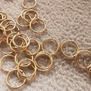 May include: A large pile of gold jump rings, a type of metal ring used in jewelry making.