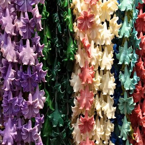 Puede incluir: Surtido de cuentas de colores en forma de flor, ensartadas en largas cadenas. Las cuentas están hechas de varios materiales, incluyendo plástico, vidrio y metal. Los colores incluyen rosa, morado, blanco, verde y rojo.