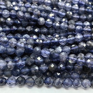 May include: A strand of blue kyanite faceted beads. The beads are round and have a smooth, polished finish.