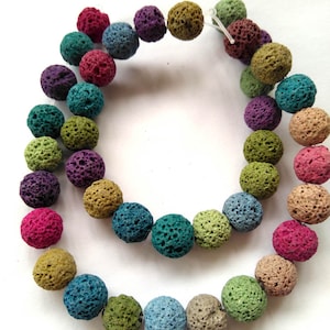 May include: A strand of colorful lava rock beads. The beads are round and have a rough, textured surface. The beads are strung on a clear elastic cord.
