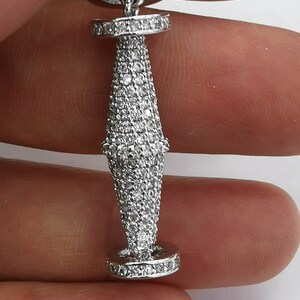 May include: A silver pendant with a teardrop-shaped design, featuring a cluster of small, clear stones. The pendant is attached to a silver chain with a circular design.