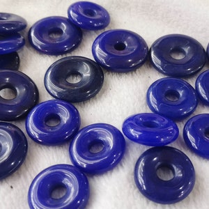 Puede incluir: Una colecci&oacute;n de 18 cuentas azules en forma de rosquilla con un agujero en el centro. Las cuentas est&aacute;n hechas de un material liso y brillante y tienen un acabado ligeramente iridiscente.