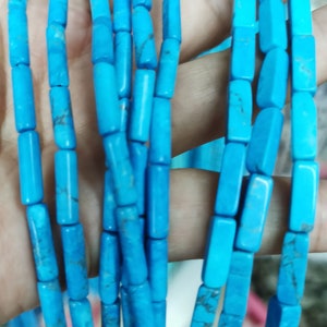 Peut inclure: Un brin de perles turquoise, chaque perle est de forme rectangulaire et de couleur bleu clair. Les perles sont enfilées sur un fil transparent.