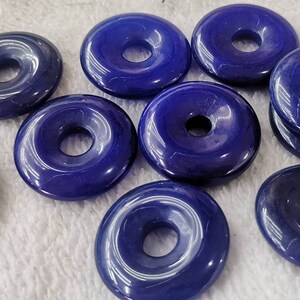 Puede incluir: Diez cuentas de piedra preciosa azules en forma de rosquilla con un agujero en el centro. Las cuentas son lisas y pulidas.