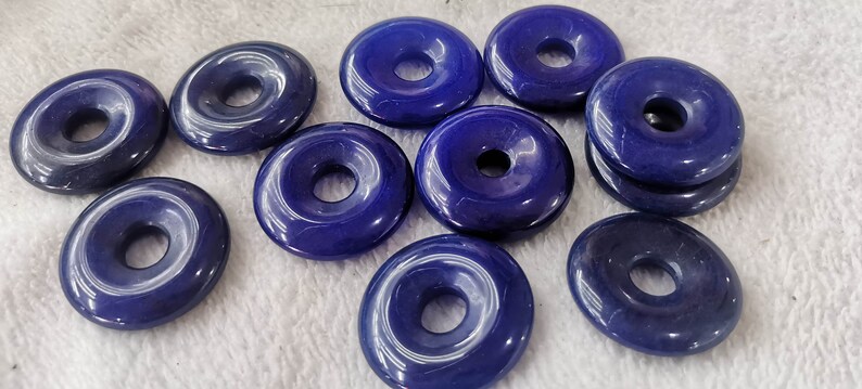 Puede incluir: Diez cuentas de piedra preciosa azules en forma de rosquilla con un agujero en el centro. Las cuentas son lisas y pulidas.