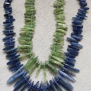 May include: Two strands of gemstone beads, one blue and one green, are strung together to form a necklace. The blue beads are long and pointed, while the green beads are shorter and more rounded.
