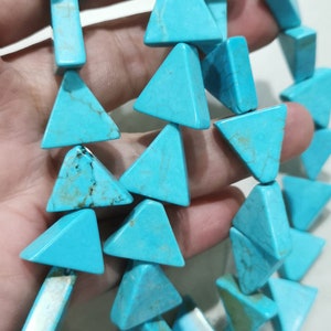May include: A strand of turquoise triangle beads. The beads are a bright blue colour and have a smooth, polished finish.