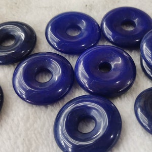 Puede incluir: Diez cuentas de piedra preciosa de color azul oscuro en forma de rosquilla con un agujero en el centro. Las cuentas son lisas y pulidas.