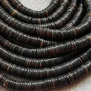 May include: A strand of black and brown shell beads, each bead is a flat disc with a slightly raised edge.