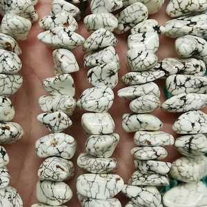 May include: A strand of white howlite gemstone beads with brown veining. The beads are irregularly shaped and have a smooth, polished finish.