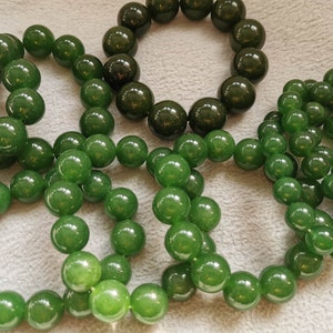 May include: Five green jade bracelets with round beads. The bracelets are made of different sizes of beads.