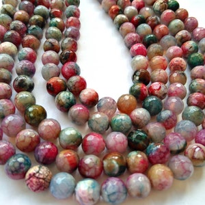 Pode incluir: Um fio de contas de ágata multicoloridas com forma facetada irregular. As contas são uma mistura de rosa, verde, marrom e branco.