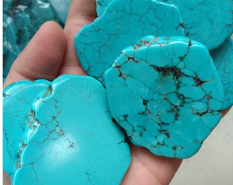 May include: A handful of polished turquoise stones. The stones are a vibrant blue-green color with dark brown veining. The irregular shapes and natural patterns of the stones are visible. The stones are smooth and appear to be ready for jewelry making or other crafts.