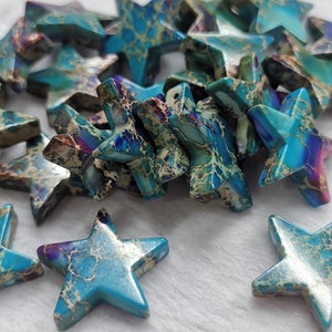 Puede incluir: Un montón de cuentas de piedra preciosa en forma de estrella de color azul, verde y dorado. Las cuentas tienen un patrón de mármol y son perfectas para hacer joyas.