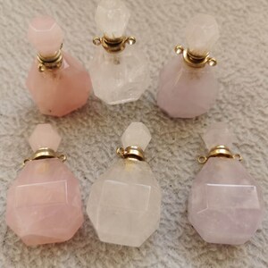 May include: Six crystal perfume bottles with gold caps. The bottles are in two colors: pink and clear. The bottles are faceted and have a geometric shape.