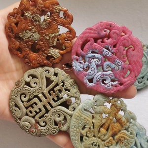 Puede incluir: Cuatro colgantes de jade tallados intrincadamente con varios diseños. Los colgantes son en tonos de verde, marrón y rosa. Los diseños incluyen un dragón, un fénix y un carácter chino.