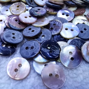 May include: Assortment of two-hole buttons in various colors and patterns, including iridescent, brown, black, and white. The buttons are made of a smooth, shiny material.