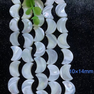 May include: A strand of white iridescent moon-shaped shell beads. Each bead measures approximately 10x14mm.