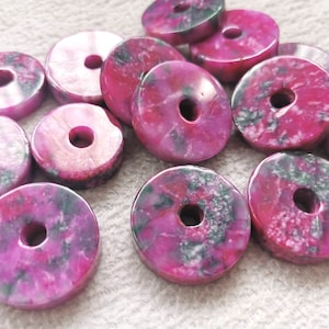 Pode incluir: Um grupo de contas de ágata rosa e verde em forma de rosquinha com um furo no centro. As contas são lisas e polidas.