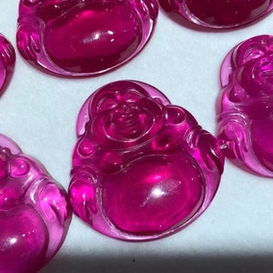 Puede incluir: Un conjunto de cinco figuritas de vidrio rosa del Buda de la Risa, cada una con una pose y expresión diferentes. Las figuritas están hechas de vidrio transparente con un tinte rosa y tienen un acabado liso y pulido.