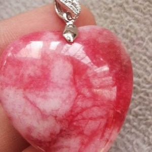 May include: A heart-shaped pendant made of pink and white marble with a silver bail. The pendant has a swirling pattern of pink and white.