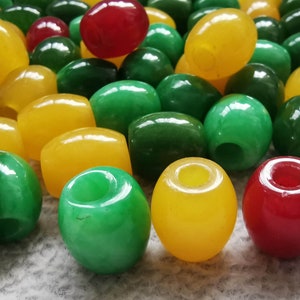 May include: A collection of smooth, round beads in yellow, green, and red colours. The beads are made of polished stone and have a hole through the centre.