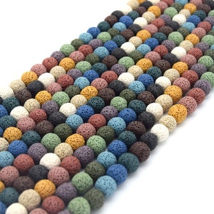 May include: A selection of round lava rock beads in a variety of colours, including beige, brown, green, blue, and yellow. The beads have a porous texture and are strung together, ideal for jewellery making or craft projects.