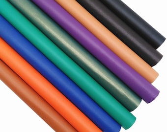 May include: An assortment of rolled sheets of colorful faux leather in various shades. Colors include brown, orange, blue, green, purple, and black. The sheets are arranged diagonally, showcasing the different hues and textures of the material.