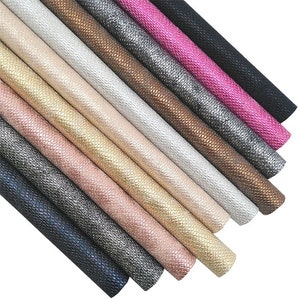 May include: A selection of rolled faux leather sheets in a range of colours, such as black, pink, silver, and gold. The sheets have a scale-like texture. The image displays the variety of shades and textures available.