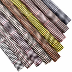 May include: A set of eight patterned fabric rolls in various colours, including black, brown, yellow, and white. The fabric has a houndstooth pattern with a plaid design.