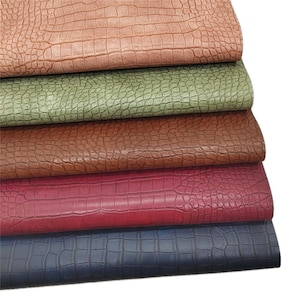 Peut inclure: Cinq morceaux de simili cuir de différentes couleurs, empilés les uns sur les autres. Le cuir a un motif gaufré crocodile. Les couleurs sont le brun, le vert, le brun foncé, le rouge et le bleu.