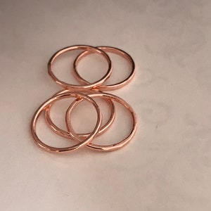 May include: Five rose gold stacking rings. The rings are simple and delicate, with a hammered texture.