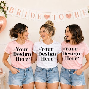 Może przedstawiać: Trzy kobiety w różowych i białych koszulkach z czarnym napisem "Your Design Here", połączonych z dżinsowymi szortami. W tle wisi baner z napisem "BRIDE TO BE", wraz z balonami i dekoracjami kwiatowymi.
