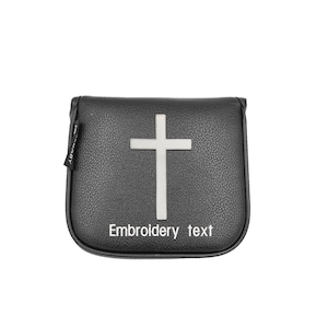 Könnte beinhalten: Schwarze Golfschlägerhaube mit weißem Kreuzdesign. Die Hülle hat eine strukturierte Oberfläche und die Worte "Embroidery text" sind unten in Weiß aufgedruckt. Ein kleines Etikett ist an der Seite befestigt.