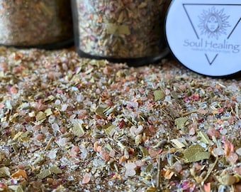 May include: Close-up of a mixture of dried herbs, flowers, and pink Himalayan salt. The mixture is in a glass jar with a black lid that says "Soul Healing".