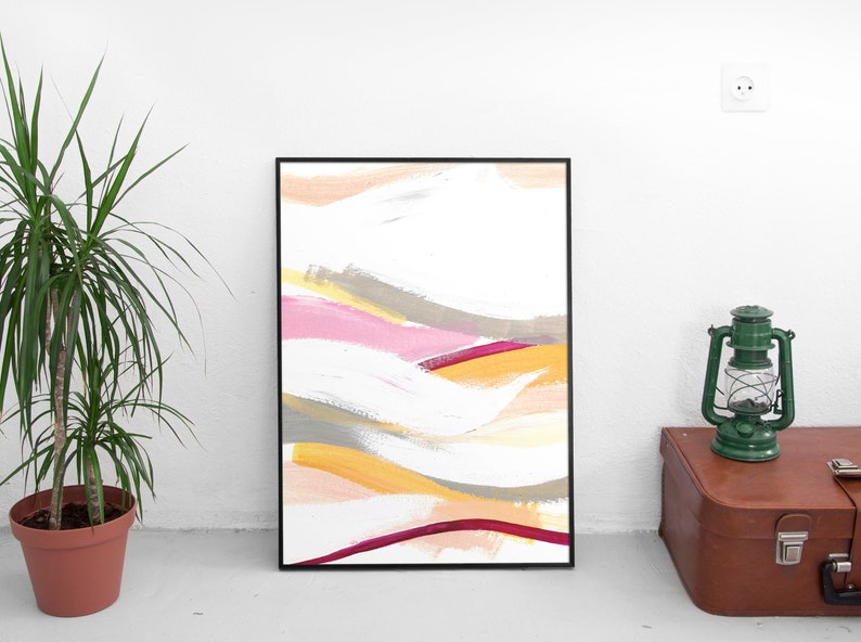 May include: Abstract painting in a black frame with a white background and colorful brushstrokes in shades of pink, yellow, orange, and gray.