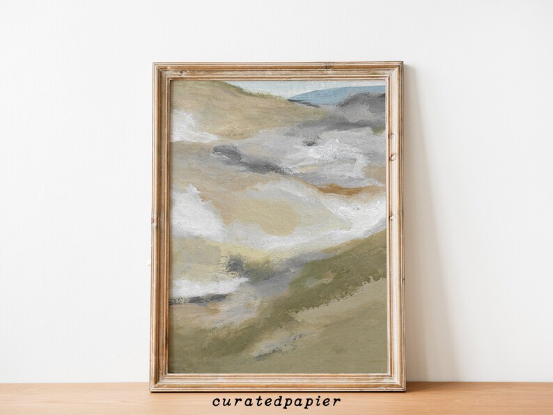 May include: Abstract landscape painting in a gold wooden frame. The artwork features a blend of neutral colors, including beige, gray, and green, with hints of blue. The painting has a textured appearance, with visible brushstrokes. The text "curatedpapier" is in the bottom left corner.