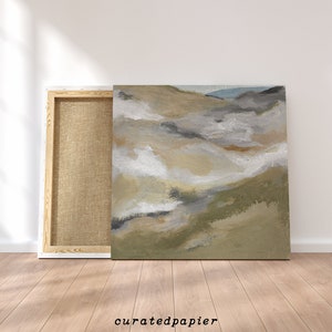 May include: An abstract landscape painting on canvas, featuring a palette of neutral tones including beige, gray, and white, with hints of green and blue. The artwork is displayed next to its wooden frame, with the text "curatedpapier" at the bottom.