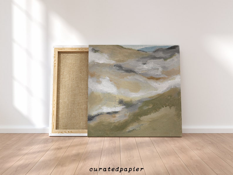 May include: An abstract landscape painting on canvas, featuring a palette of neutral tones including beige, gray, and white, with hints of green and blue. The artwork is displayed next to its wooden frame, with the text "curatedpapier" at the bottom.
