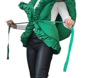 May include: A bright green, puffy jacket with a ruffled design and long ties. The jacket is paired with black leather pants and black platform boots. The outfit is set against a white background.