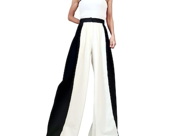 Puede incluir: Un conjunto de dos piezas que presenta un top blanco sin mangas con ribete negro y una cinturilla negra. Los pantalones de pernera ancha están divididos en tres secciones verticales: negro en los laterales y blanco en el centro. El conjunto está diseñado para un look elegante y moderno.