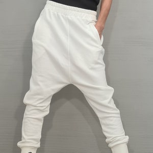 Op de afbeelding: Een zwart geribbeld tanktop met witte rand is gecombineerd met een witte broek met lage kruis. De outfit wordt gecompleteerd met witte sneakers met zwarte veters. De kleding is casual en comfortabel.