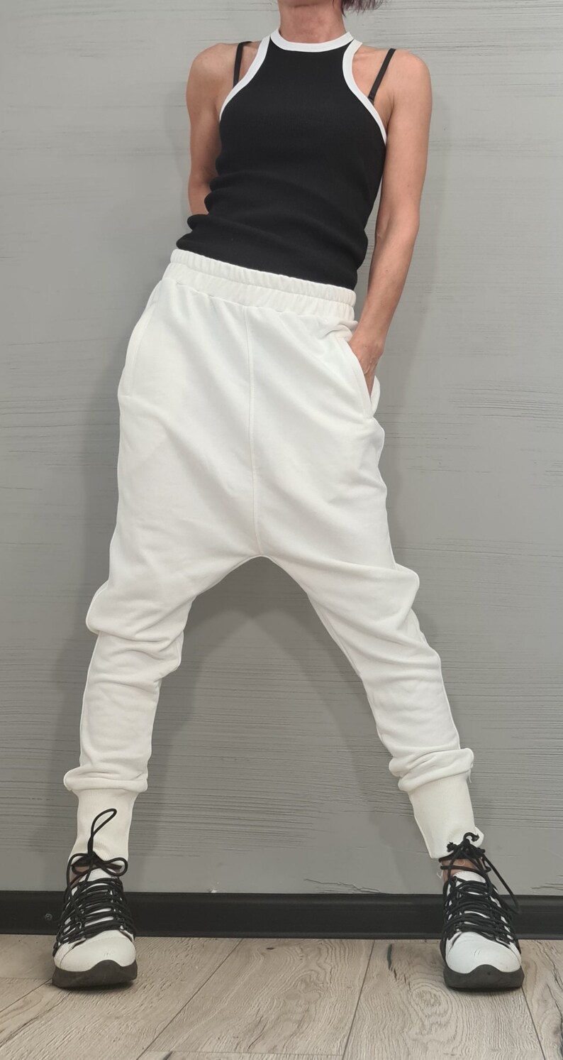 Op de afbeelding: Een zwart geribbeld tanktop met witte rand is gecombineerd met een witte broek met lage kruis. De outfit wordt gecompleteerd met witte sneakers met zwarte veters. De kleding is casual en comfortabel.